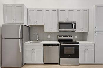 A kitchen with white cabinets and appliances.
